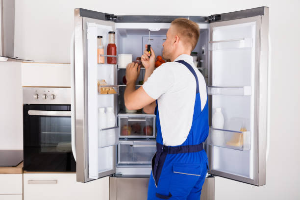 Male Technician Repairing Broken Refrigerator Appliance With Screwdriver